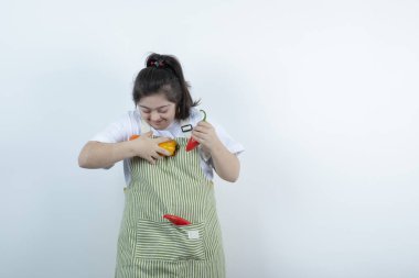 Kareli önlüğün içinde duran ve cebine sebze koyan genç ve güzel bir kız. Yüksek kalite fotoğraf