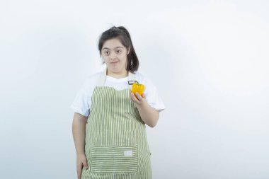 Kareli önlüğün içinde elinde sarı dolmalık biber tutan genç ve güzel bir kız. Yüksek kalite fotoğraf