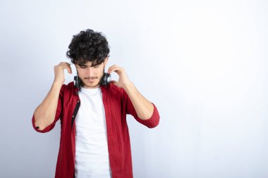 Kulaklıklı bir gencin beyaz arka plandaki dezavantajına baktığı bir görüntü. Yüksek kalite fotoğraf