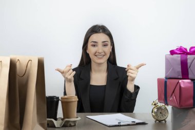 İş yerinde elinde hediyelerle oturan iş kadınının portresi.