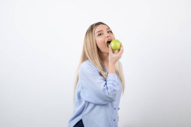 Çekici bir kadın modelin yeşil bir elmayı yerken çekilmiş portresi. Yüksek kalite fotoğraf