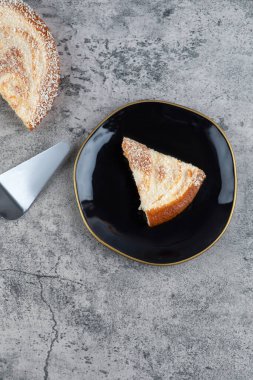 Mermer zemin üzerinde lezzetli bir parça kek olan siyah bir tabak. Yüksek kalite fotoğraf