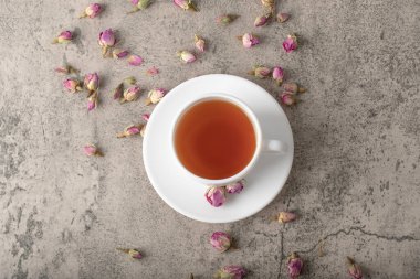 Taş yüzeyinde kurumuş güller olan bir fincan siyah sıcak çay. Yüksek kalite fotoğraf