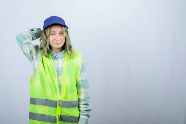 Üniformalı genç bayan mimar beyaz duvarın üzerinde mutlu bir ifadeyle duruyor. Yüksek kalite fotoğraf