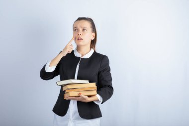 Beyaz arka plan üzerine düşünen bir sürü kitabı olan genç bir öğrenci. Yüksek kalite fotoğraf