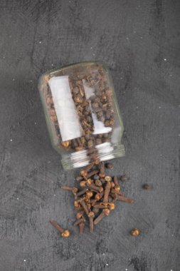 Siyah yüzeydeki cam kavanozdan kurumuş doğal karanfil yığını. Yüksek kalite fotoğraf