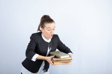 Beyaz arka plan üzerine kitapları tutmaya çalışan genç bir öğrenci görüntüsü. Yüksek kalite fotoğraf