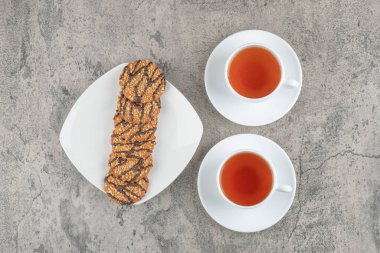 Üzerine tohum serpiştirilmiş taze yulaf ezmeli kurabiyeler ve iki fincan siyah çay. Yüksek kalite fotoğraf