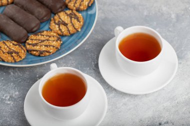 Taş masaya konmuş bir fincan sıcak çayla çeşitli tatlı atıştırmalıklar. Yüksek kalite fotoğraf