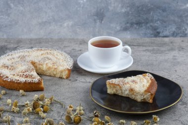 Lezzetli bir parça kek ve beyaz bir fincan sıcak çay ile siyah bir tabak. Yüksek kalite fotoğraf