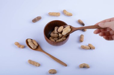 Beyaz arka planda soyulmamış fıstık kaşığı tutan bir kadın. Yüksek kalite fotoğraf