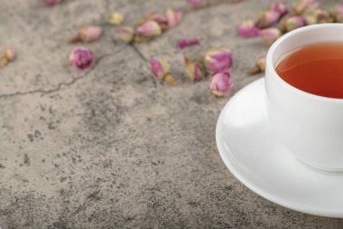 Taş yüzeyinde kurumuş güller olan bir fincan siyah çay. Yüksek kalite fotoğraf