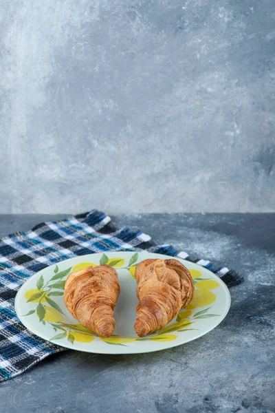 Mermer bir arka plana yerleştirilmiş renkli bir tabak taze kruvasan. Yüksek kalite fotoğraf