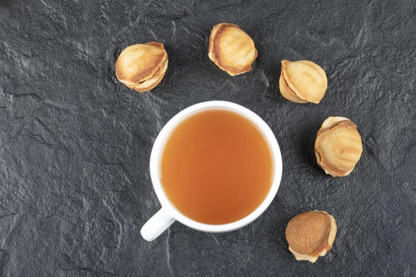 Ceviz şeklinde kurabiyeler ve siyah arka planda bir fincan sıcak çay. Yüksek kalite fotoğraf