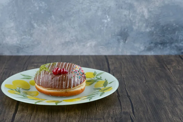 Tahta yüzeyde limon desenli tabakta çikolatalı donut. Yüksek kalite fotoğraf