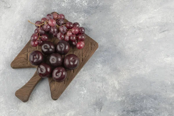 Holztafel Mit Frischen Roten Pflaumen Und Trauben Auf Marmoroberfläche Hochwertiges — Stockfoto