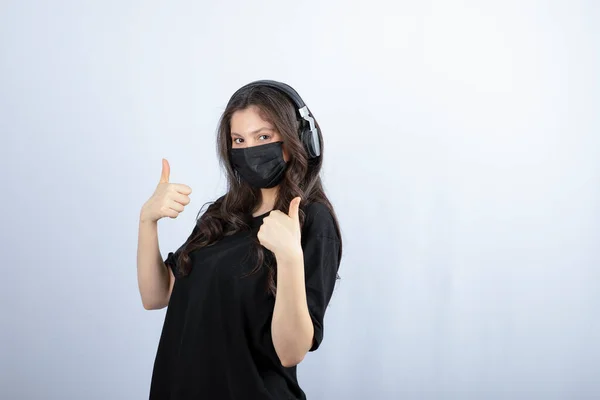 Жінка Медичній Масці Слухає Музику Навушниках Показує Пальці Вгору Фотографія — стокове фото