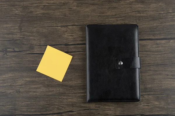 Ahşap arka planda not defteri olan sarı kare çıkartma. Yüksek kalite fotoğraf