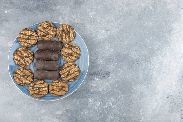Mavi tabak dolusu çikolatalı kek ve mermer yüzeyde kepekli kurabiye. Yüksek kalite fotoğraf