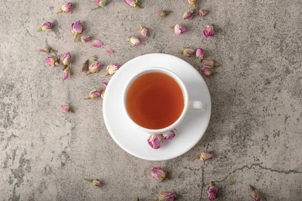 Taş yüzeyinde kurumuş güller olan bir fincan siyah sıcak çay. Yüksek kalite fotoğraf