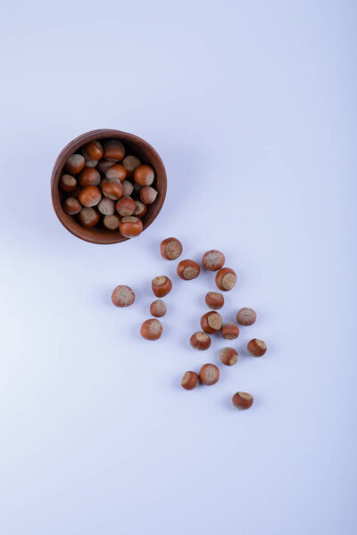 Clay bowl of shelled organic hazelnuts on white background. High quality photo