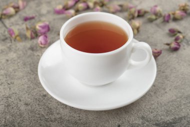 Taş yüzeyinde kurumuş güller olan bir fincan siyah çay. Yüksek kalite fotoğraf