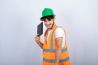 Yeşil şapkalı genç mühendis elinde siyah defter ve ayakta duruyor. Yüksek kalite fotoğraf