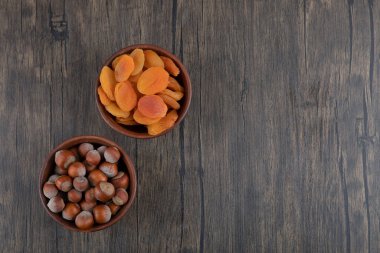 Tahta masada kurutulmuş kayısı meyveleri ve sağlıklı fındıklarla dolu tahta kaseler. Yüksek kalite fotoğraf