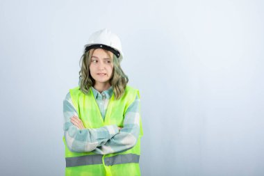 Beyaz fonda duran beyaz şapkalı genç inşaat işçisinin görüntüsü. Yüksek kalite fotoğraf