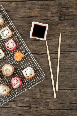 Çeşitli suşi çeşitleri, yemek çubukları ve soya sosuyla ahşap arka planda. Yüksek kalite fotoğraf