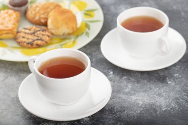 Tabakta tatlı abur cuburlar ve arka planda beyaz çay fincanları. Yüksek kalite fotoğraf