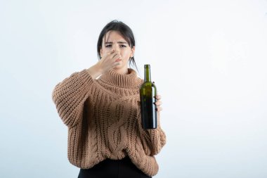 Kokusu yüzünden burnunu tutan şarap şişesiyle genç bir kadının portresi. Yüksek kalite fotoğraf
