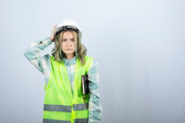 Not defteriyle beyaz duvarda poz veren güzel bir kadın mühendis resmi. Yüksek kalite fotoğraf