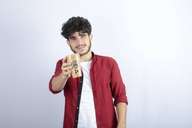 Beyaz duvarda mola vermek için elinde kahve tutan esmer adamın fotoğrafı. Yüksek kalite fotoğraf