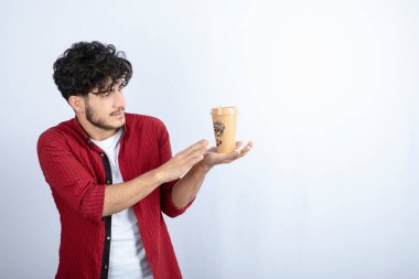 Beyaz arka planda duran bir fincan kahveyle genç bir adamın portresi. Yüksek kalite fotoğraf