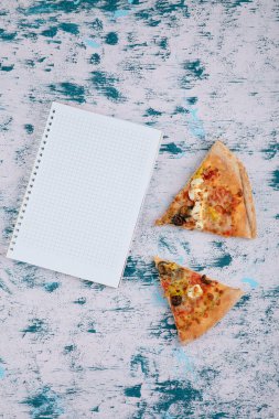 Mermer zemin üzerinde defter olan sıcak pizza dilimleri. Yüksek kalite fotoğraf