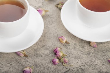 Taş yüzeyinde kurumuş güller olan siyah sıcak çay fincanları. Yüksek kalite fotoğraf