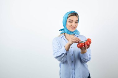 Mavi şallı, kırmızı domatesli genç bir kadın resmi. Yüksek kalite fotoğraf