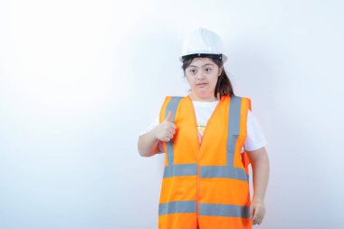 Beyaz duvarın üzerinde duran kasklı genç bayan inşaat işçisi. Yüksek kalite fotoğraf