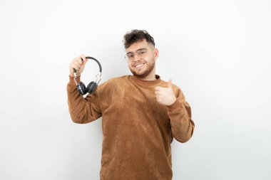 Siyah kulaklık takan ve onaylayan genç bir erkek manken resmi. Yüksek kalite fotoğraf