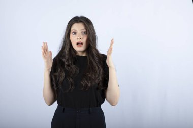 Beyaz arka plandaki bir şeye şaşıran uzun saçlı bir kızın görüntüsü. Yüksek kalite fotoğraf