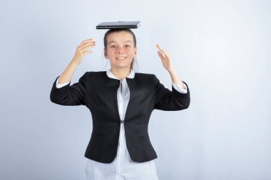 Genç ve güzel bir kız beyaz arka planda kafasında kitap tutuyor. Yüksek kalite fotoğraf