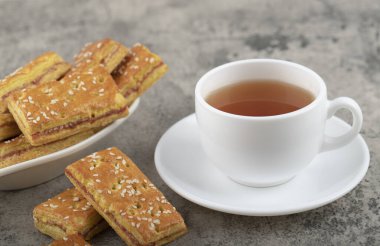 Taş bir masanın üzerine kraker konmuş beyaz fincan sıcak çay. Yüksek kalite fotoğraf