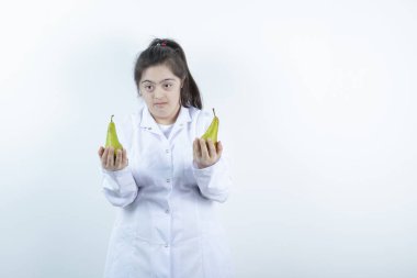 Doktor üniformalı genç kız elinde armut meyvesi tutuyor. Yüksek kalite fotoğraf