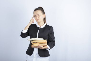 Beyaz arka plan üzerine düşünen bir sürü kitabı olan genç bir öğrenci. Yüksek kalite fotoğraf