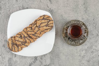 Susam tohumlu bir tabak kurabiye ve mermer yüzeyde bir fincan siyah çay. Yüksek kalite fotoğraf