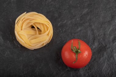 Siyah yüzeyde taze domatesli çiğ tagliatelle yuvaları. Yüksek kalite fotoğraf