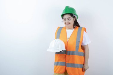 Beyaz duvarın üzerinde miğfer tutan kasklı genç bayan inşaat işçisi. Yüksek kalite fotoğraf