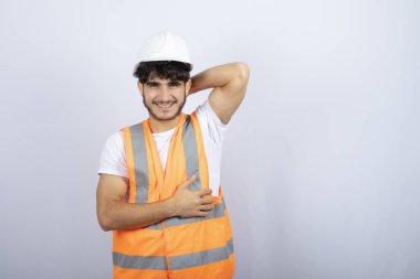 Beyaz kasklı yakışıklı genç adam beyaz duvarın üzerinde kameraya poz veriyor. Yüksek kalite fotoğraf