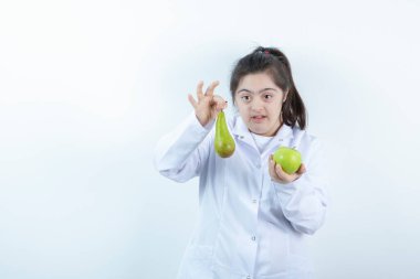 Doktor üniformalı genç bir kız elinde yeşil elmalı armut meyvesi tutuyor. Yüksek kalite fotoğraf
